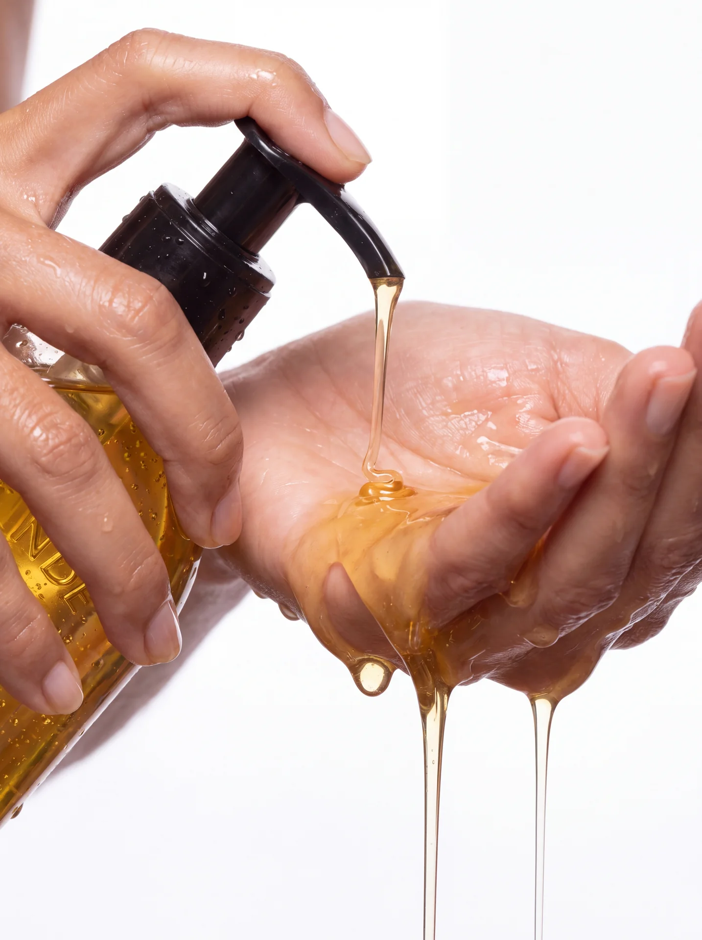 Golden shower oil pouring from the pump into an open palm, MARSE beauty concept