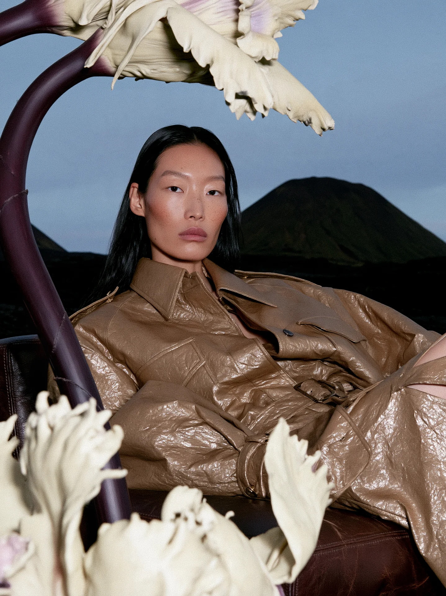 Bronze-brown leather look framed by giant white orchid stems in a dark landscape
