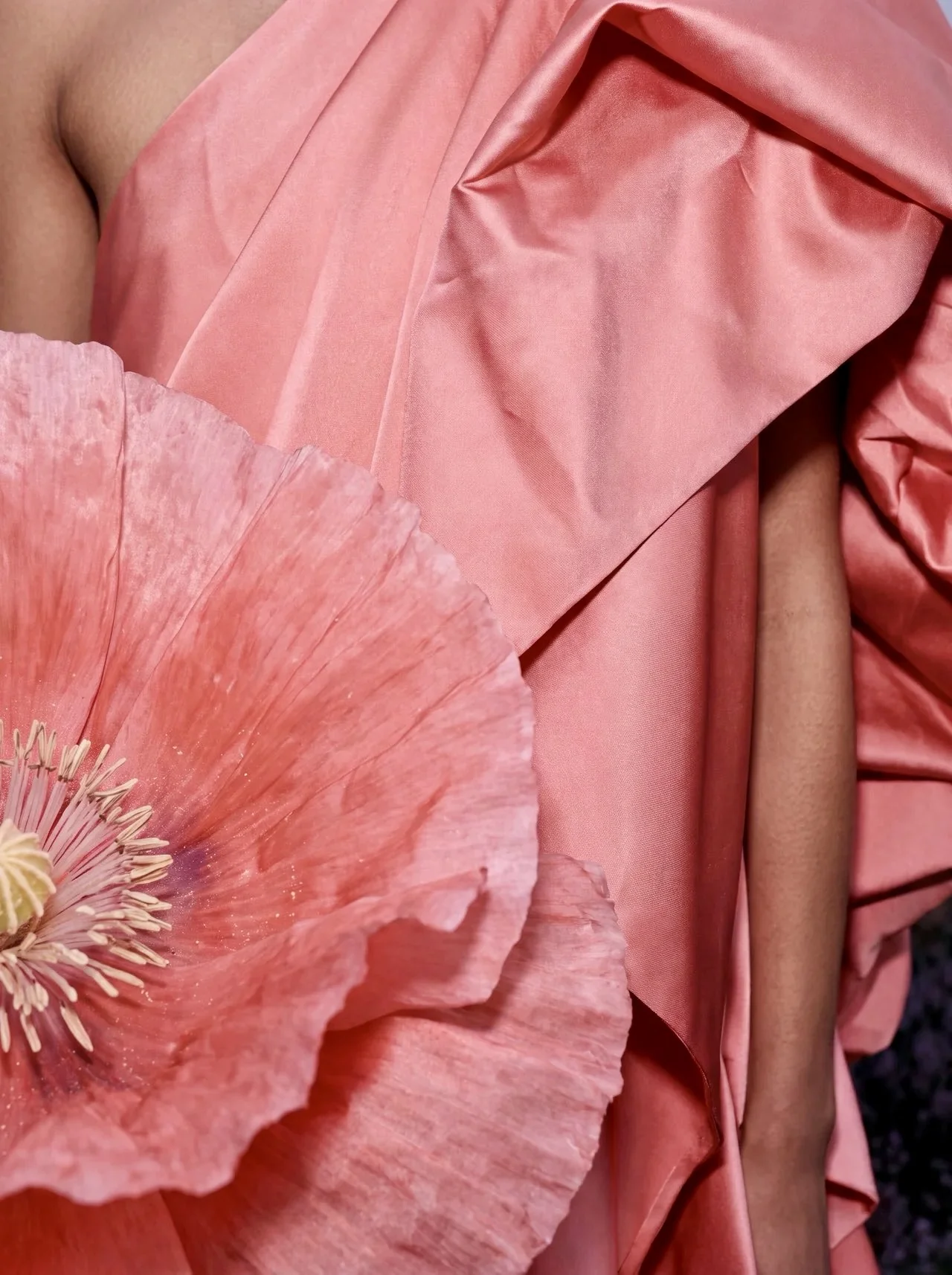 Oversized poppy bloom against pink dress fabric, close-up
